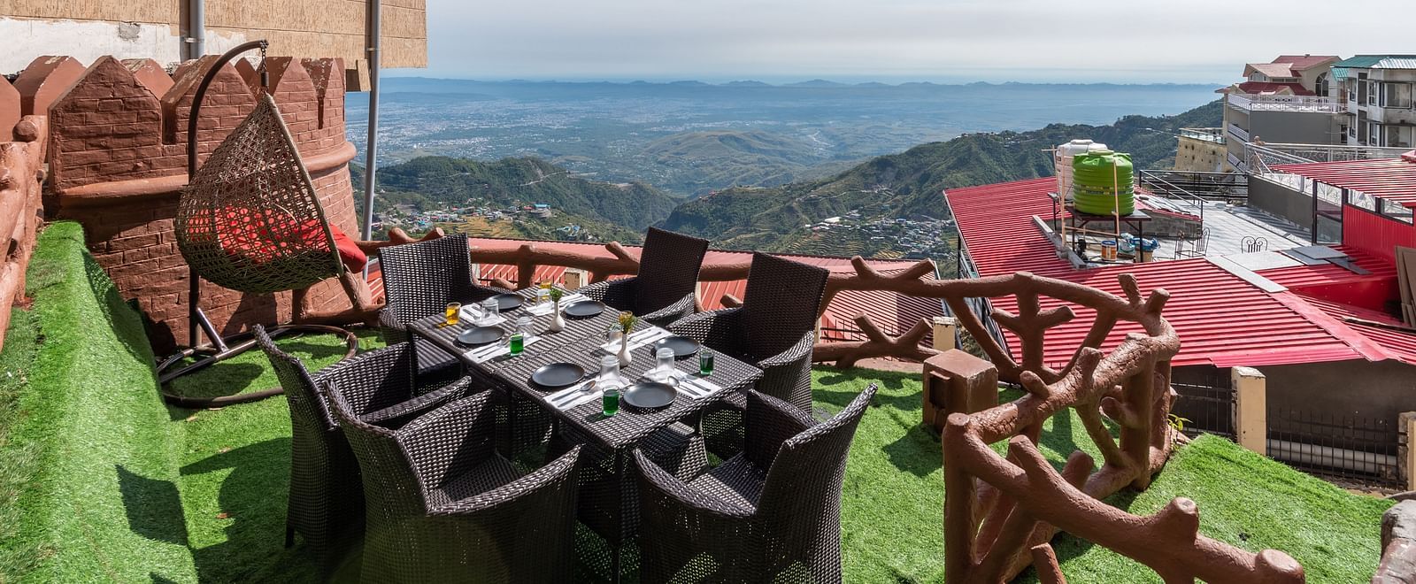 An outdoor dining area with a table and chairs set on a grassy terrace overlooking a scenic mountain landscape | DLS The Pearl